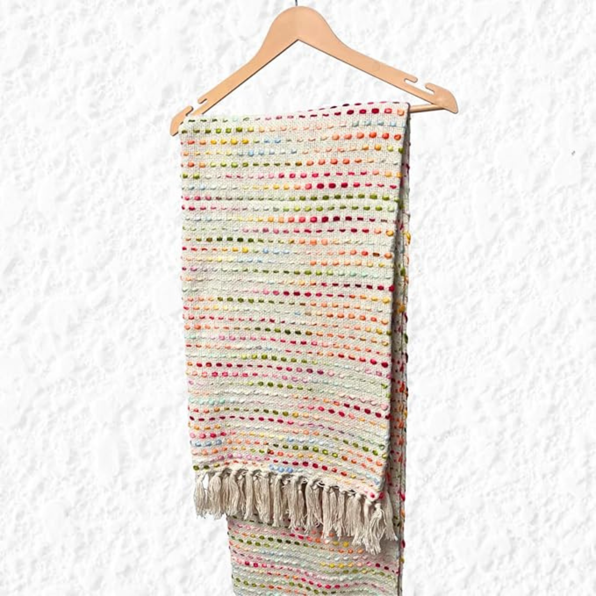 Colorful woven blanket with tassels on a wooden hanger against a white background