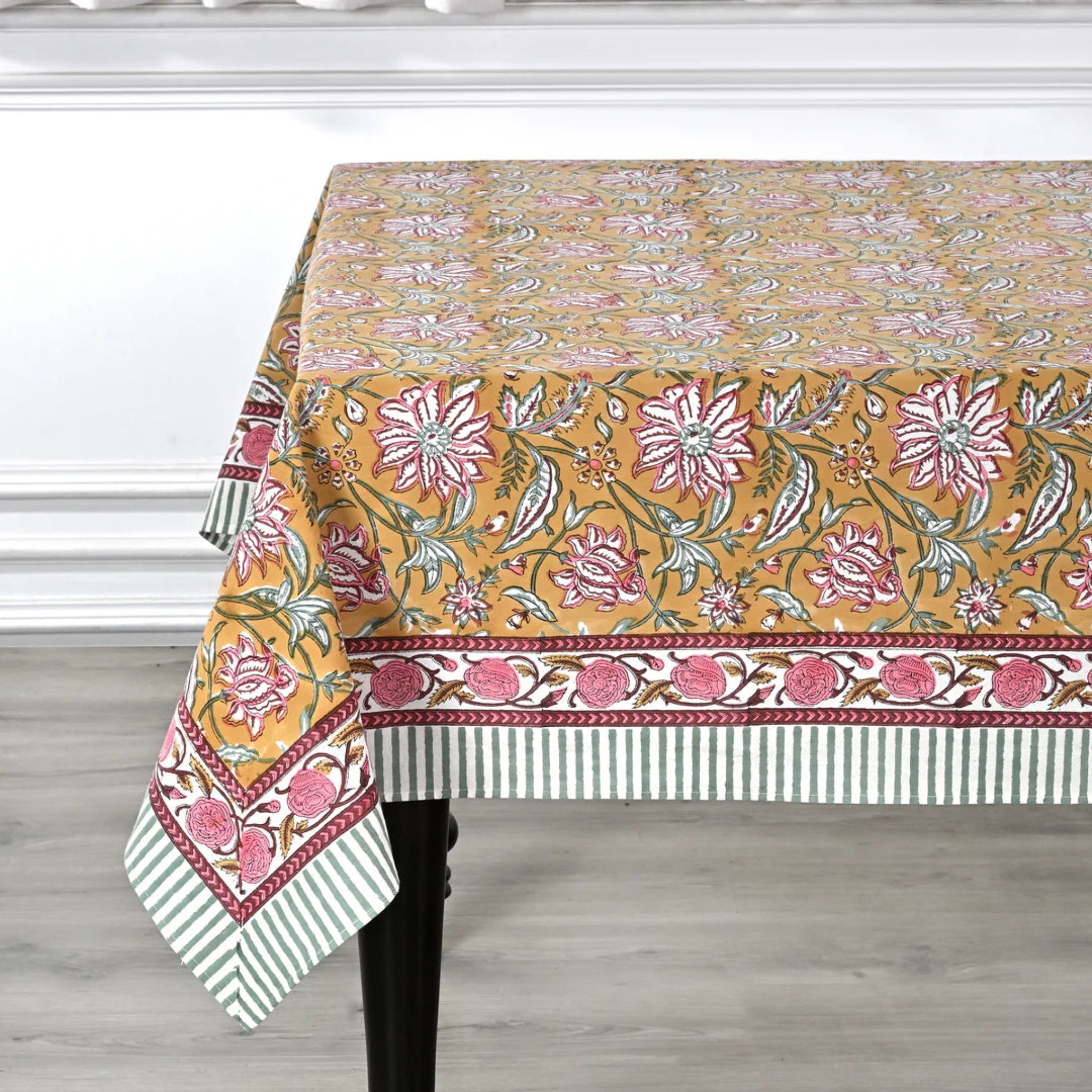Decorative floral tablecloth on a wooden table with a white background