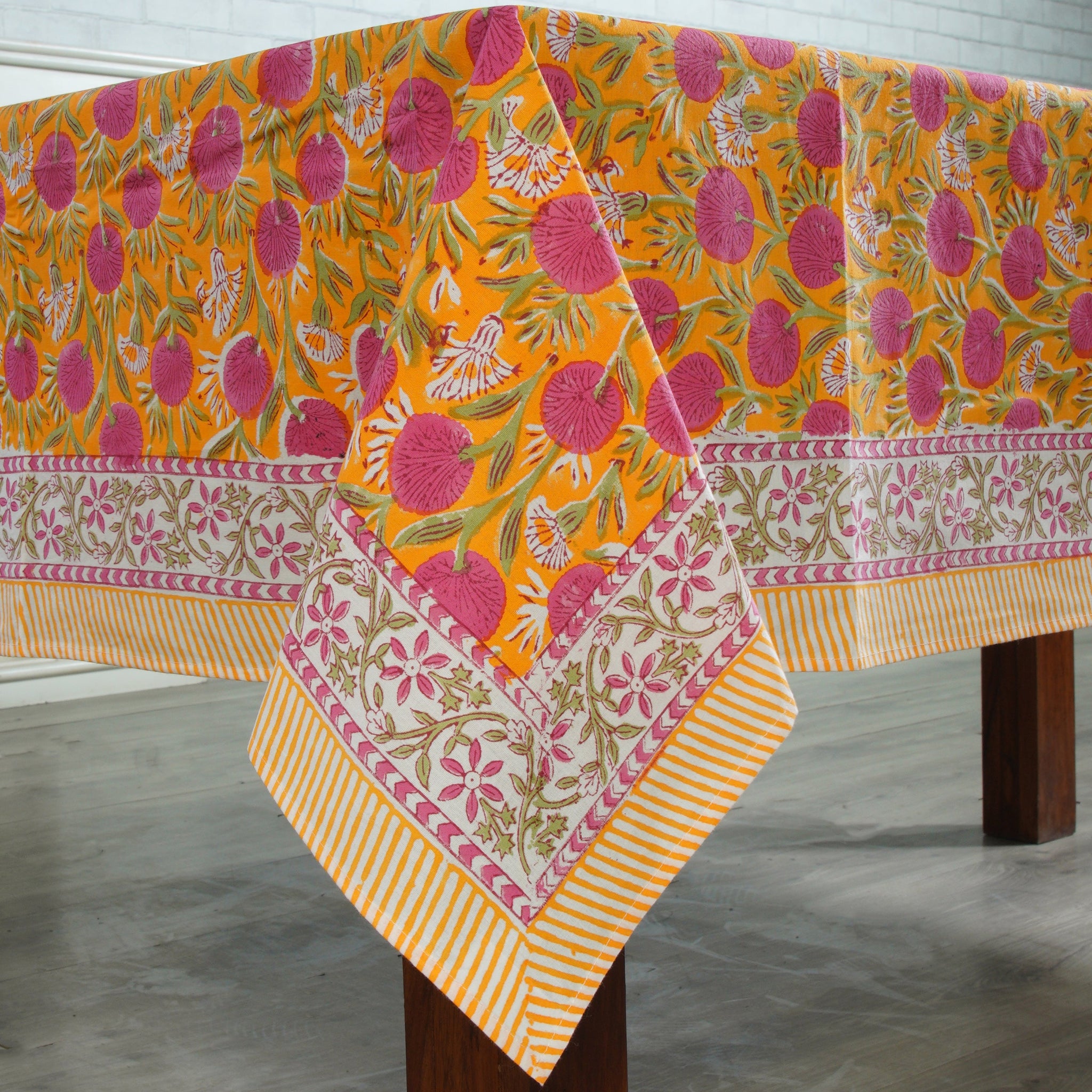 Colorful floral-patterned tablecloth on a wooden table with a white background