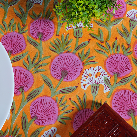 Patterned fabric with pink flowers and green leaves on an orange background