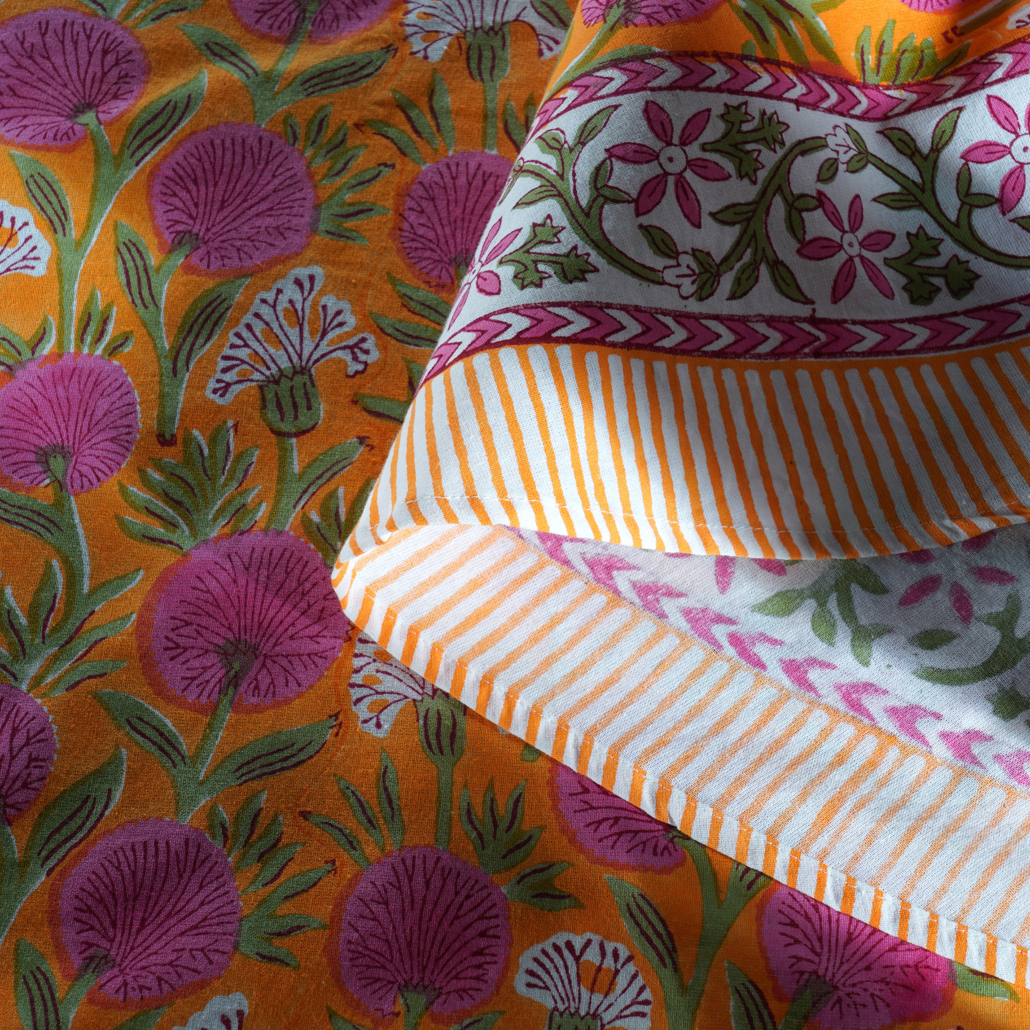 Close-up of colorful fabric with floral and striped patterns on an orange background