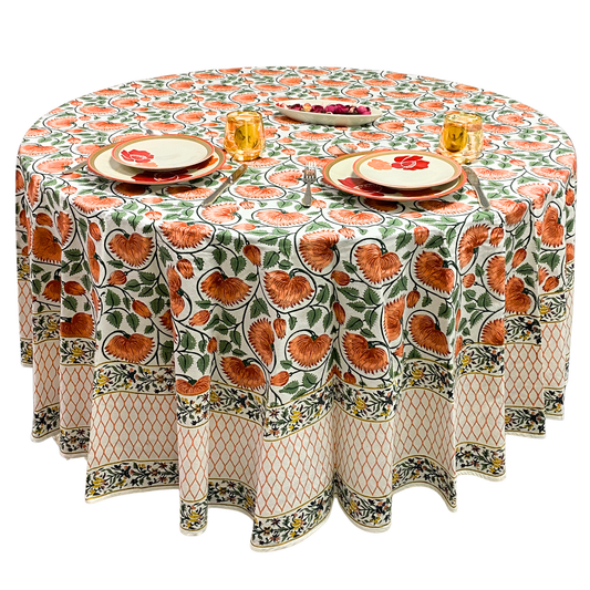 Round table with a patterned tablecloth featuring orange floral designs on a white background