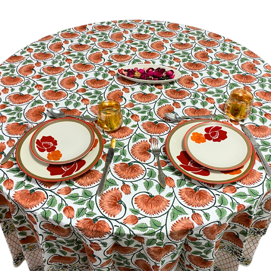 Table setting with floral tablecloth, plates, and cutlery on a white background