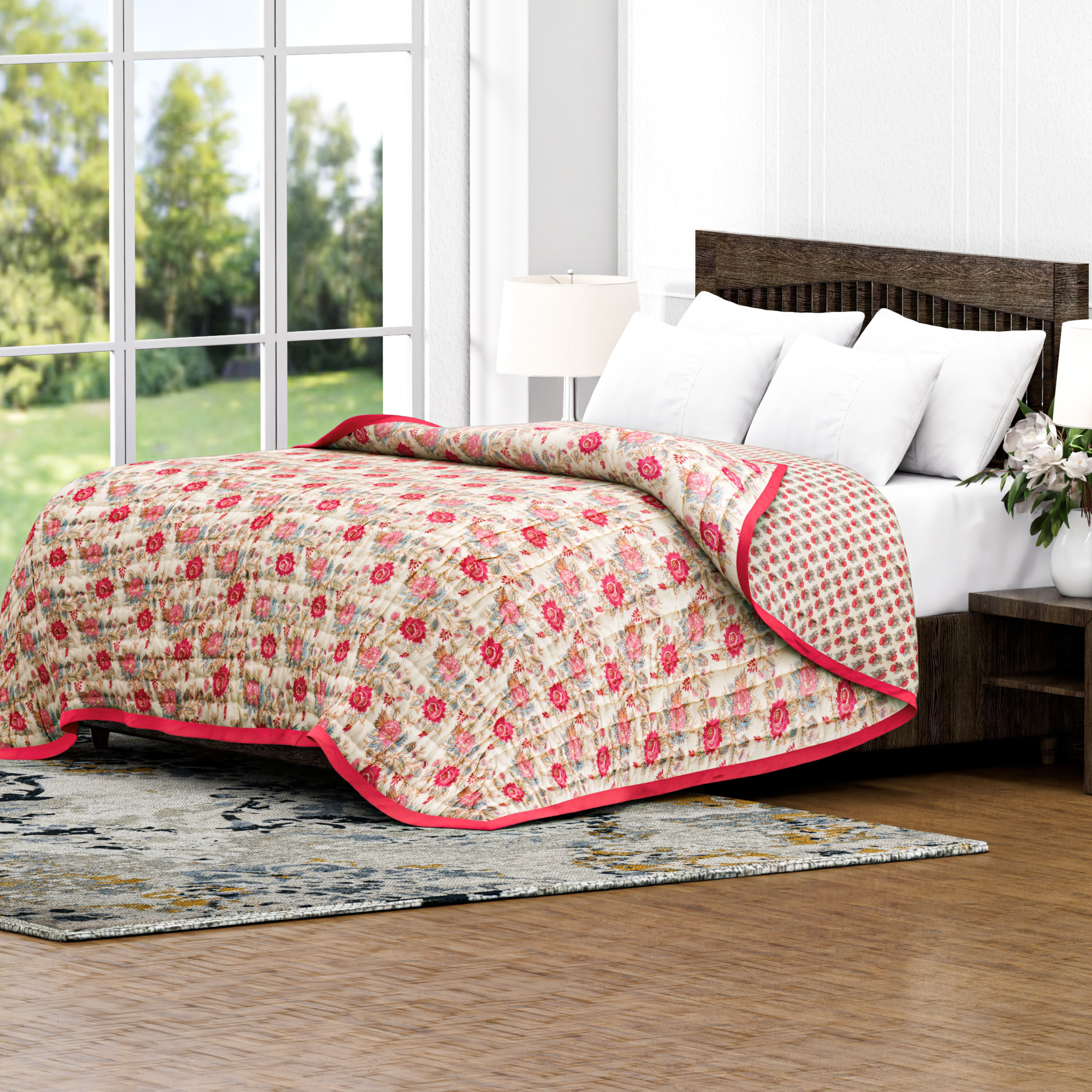 Floral quilt on a bed in a bright room with large windows.