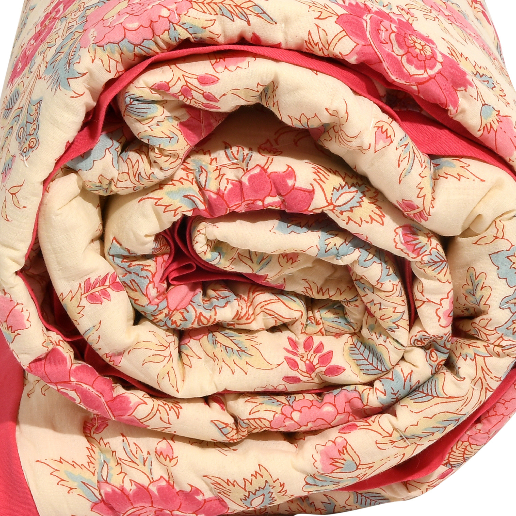 Rolled-up floral quilt with pink and beige pattern on a white background