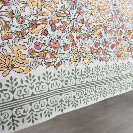Floral patterned fabric with a geometric border on a wooden floor.