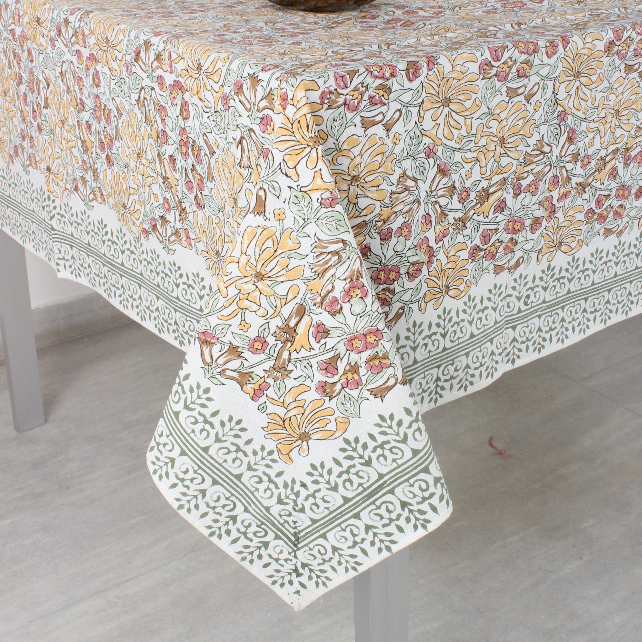 Floral patterned tablecloth on a dining table with a vase.