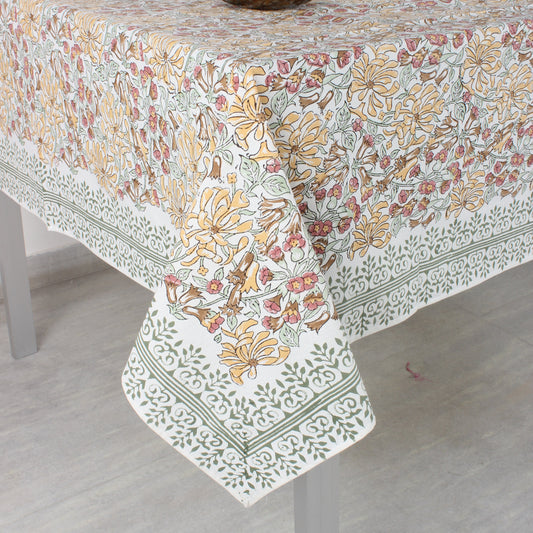 Floral patterned tablecloth on a dining table with a vase.