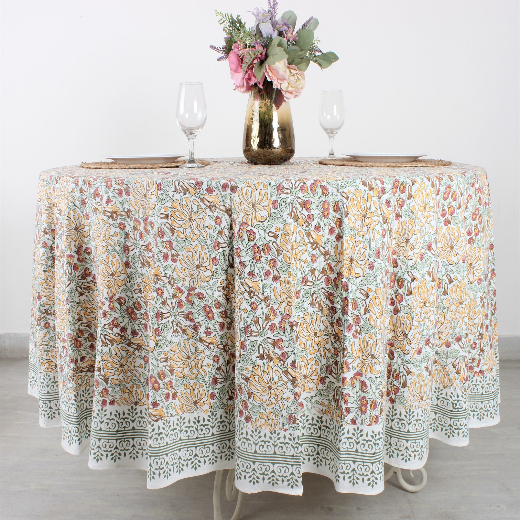 Round table with a floral patterned tablecloth on a light background