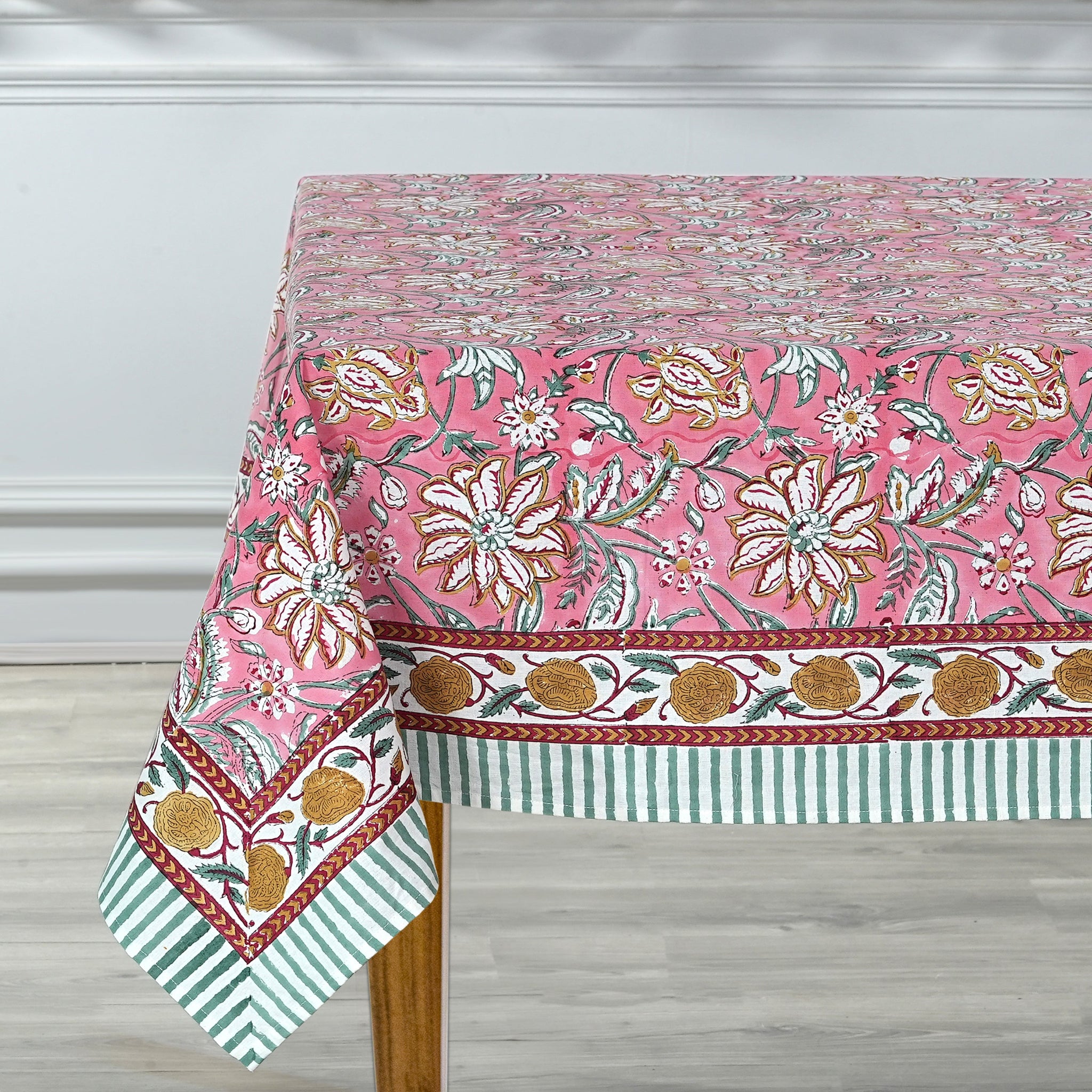 Floral patterned tablecloth on a wooden table with a white wall background
