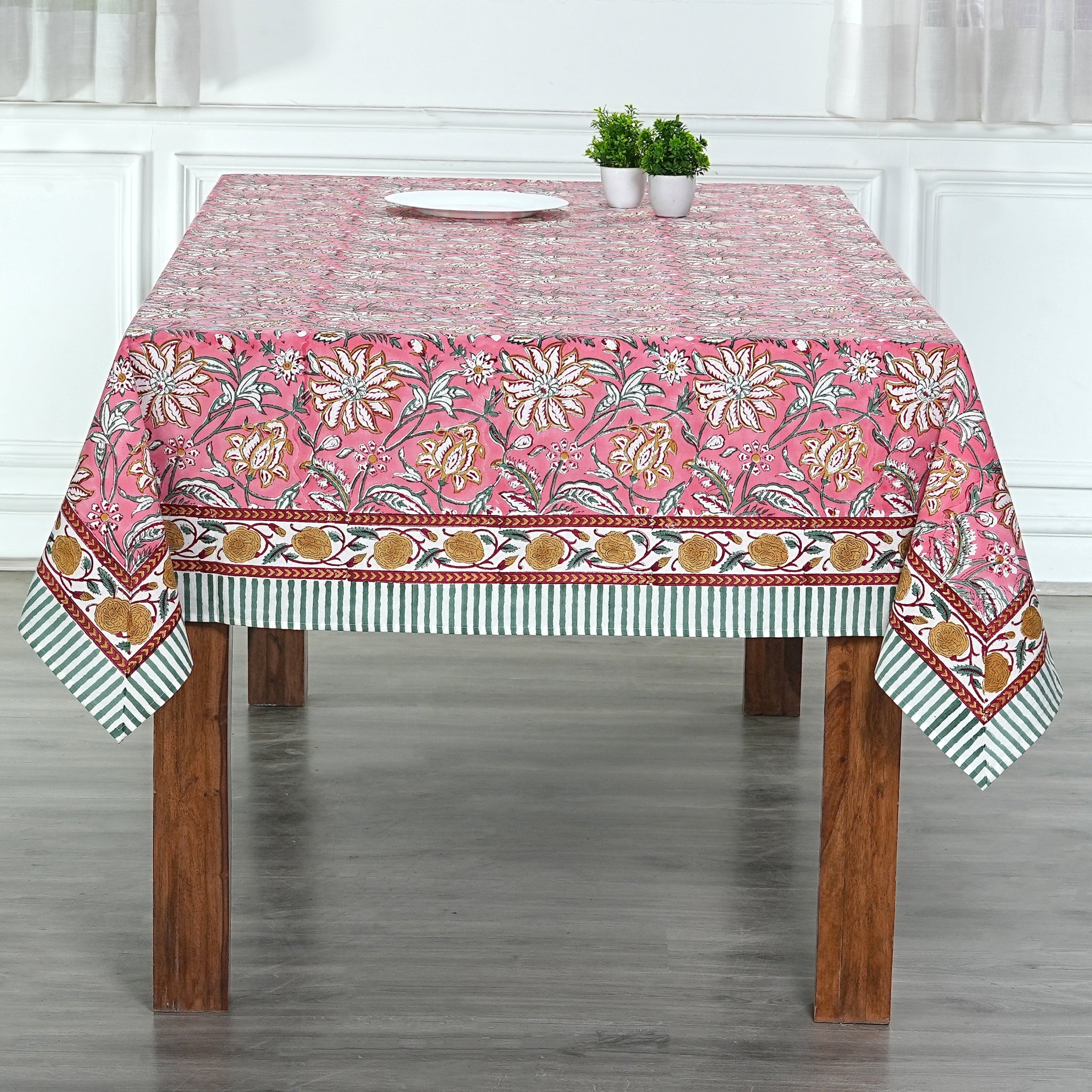 Tablecloth with floral pattern on a wooden table in a room.