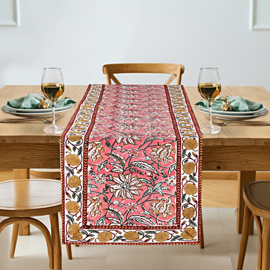Dining table set with a floral-patterned table runner, glasses, and plates.