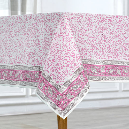 Pink and white patterned tablecloth on a wooden table with a white curtain background