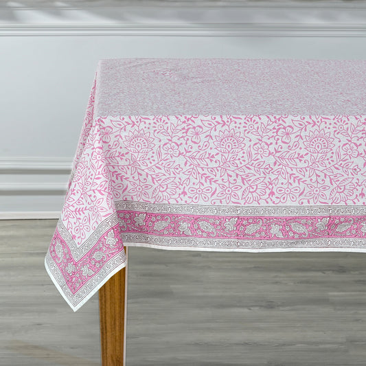 Tablecloth with pink and white floral pattern on a wooden table against a gray wall.