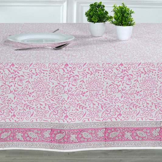 Tablecloth with pink floral pattern on a table setting with plates and utensils.