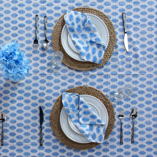 Table setting with blue and white patterned napkins on a blue tablecloth.