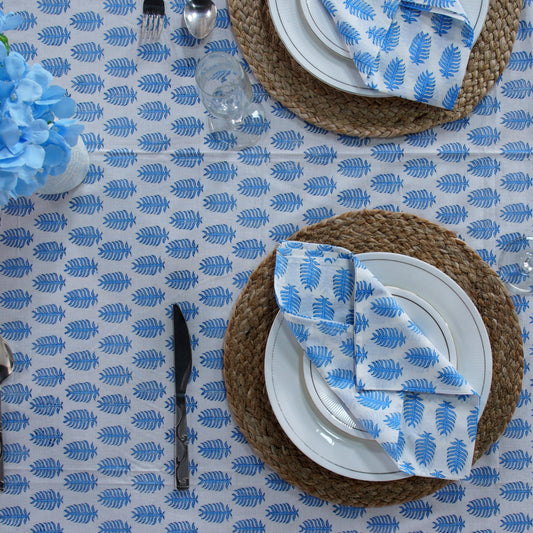 Table setting with blue and white patterned tablecloth, plates, and cutlery.