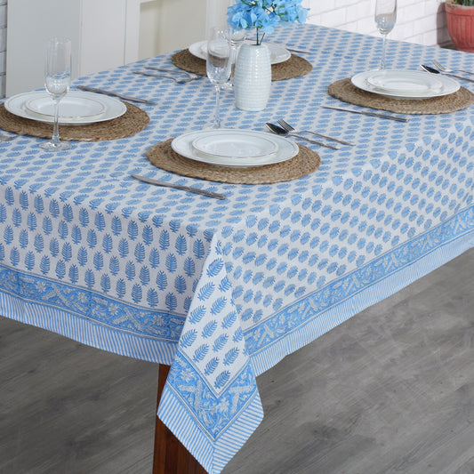 Dining table set with a blue and white patterned tablecloth, plates, and cutlery.