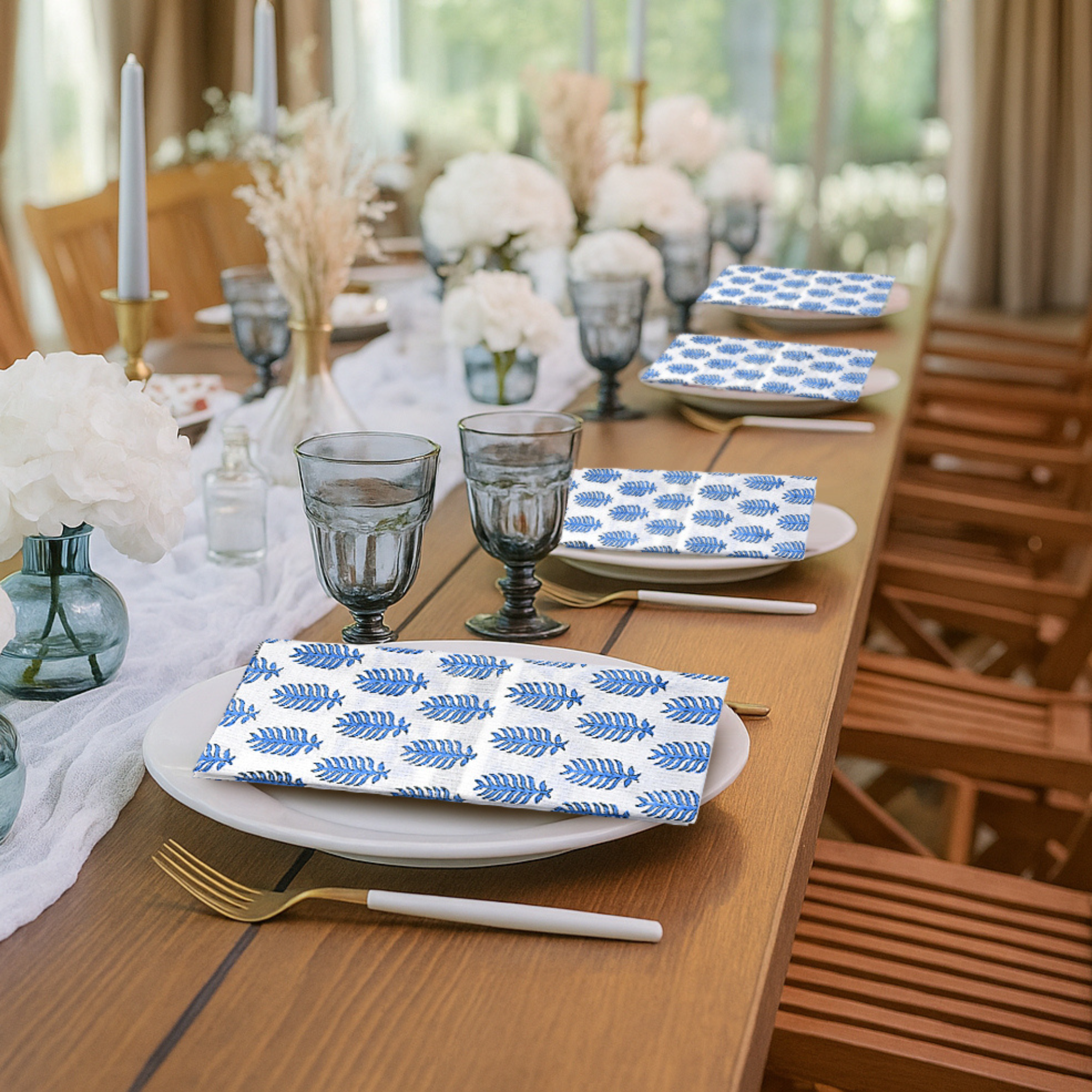 Dining table set with blue and white patterned plates, glasses, and napkins.