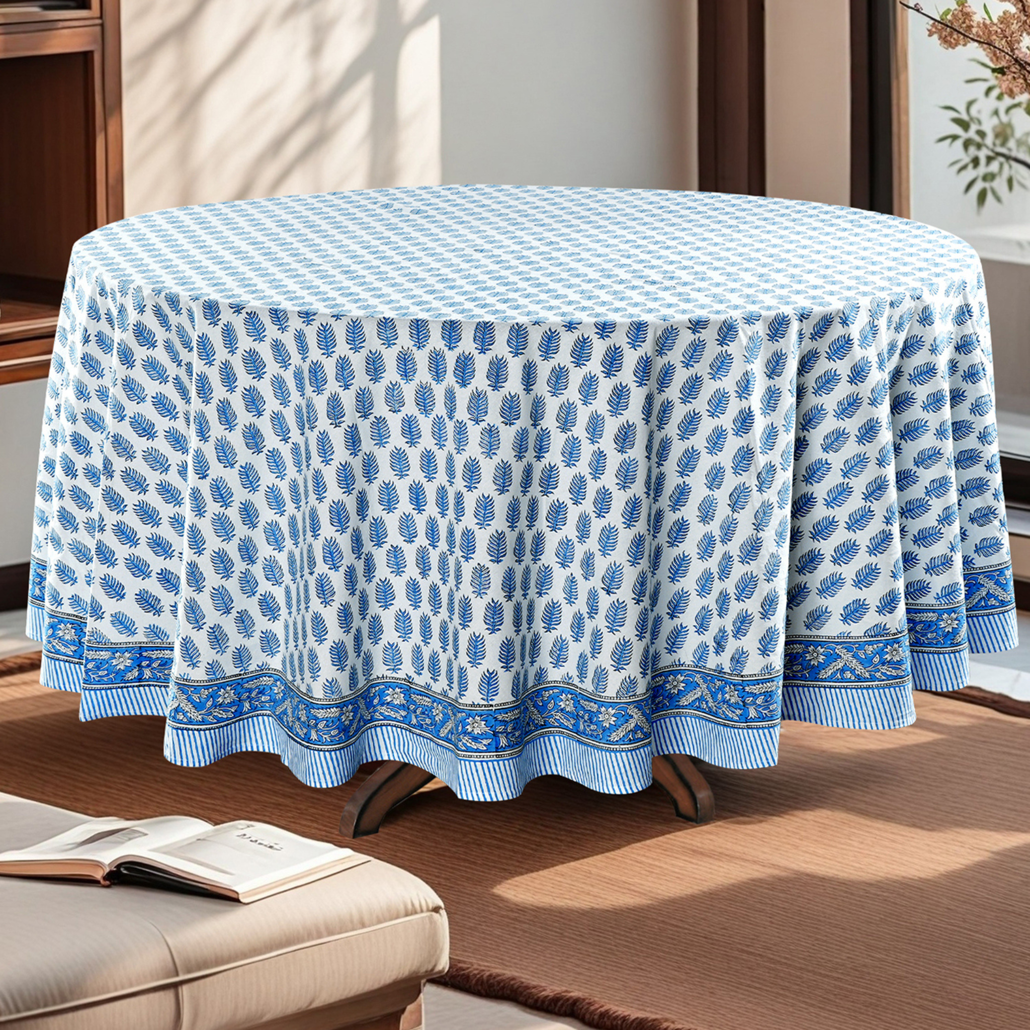 Round table covered with a blue and white patterned tablecloth in a living room setting.