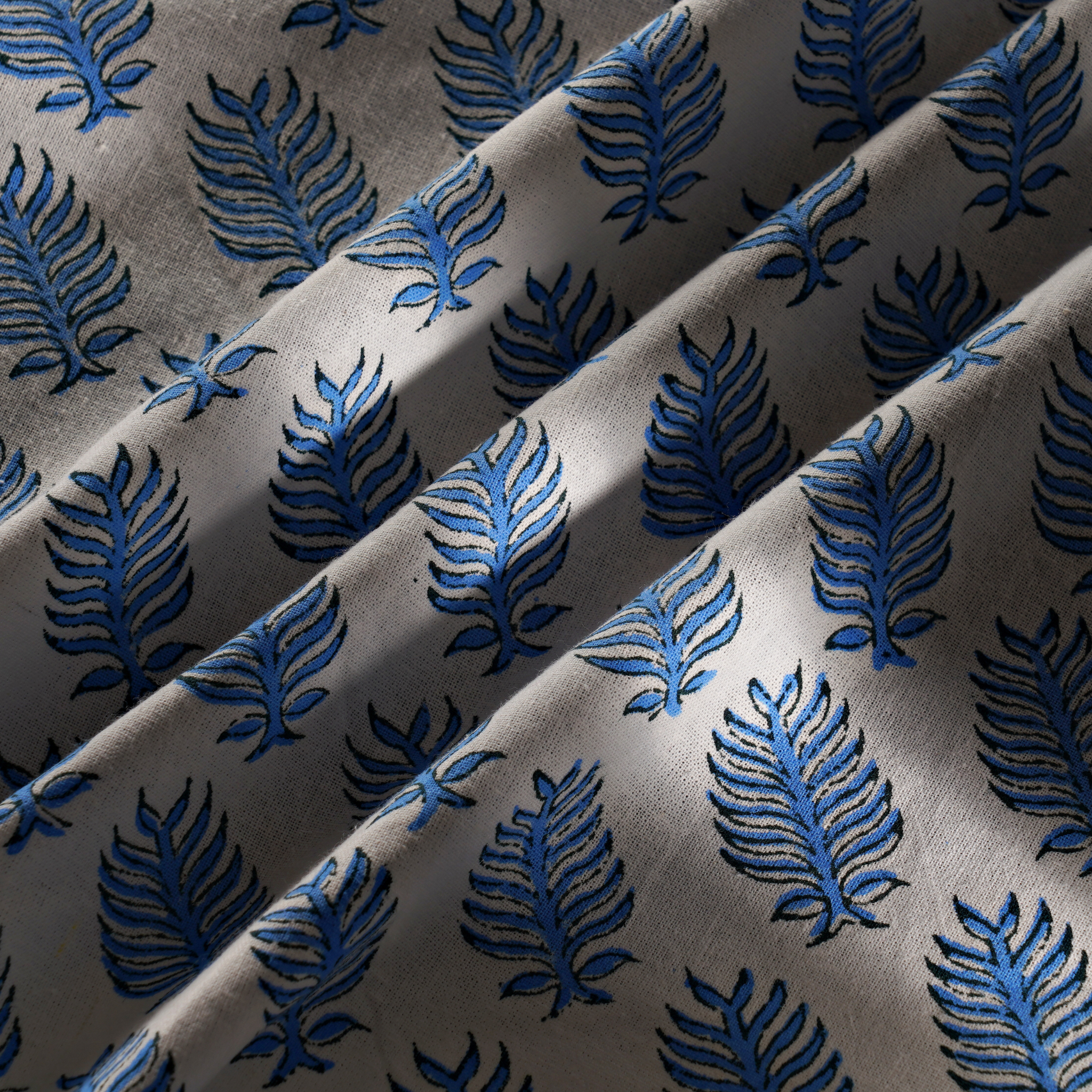 Close-up of fabric with blue leaf pattern on gray background