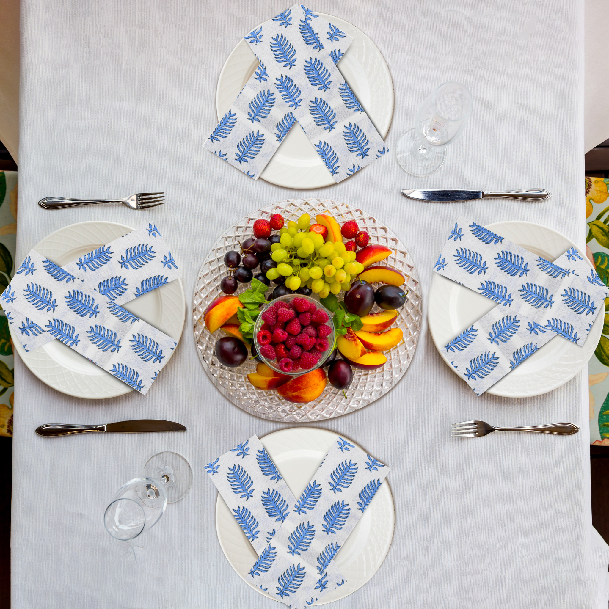 Table setting with fruit platter and patterned napkins on a white tablecloth.