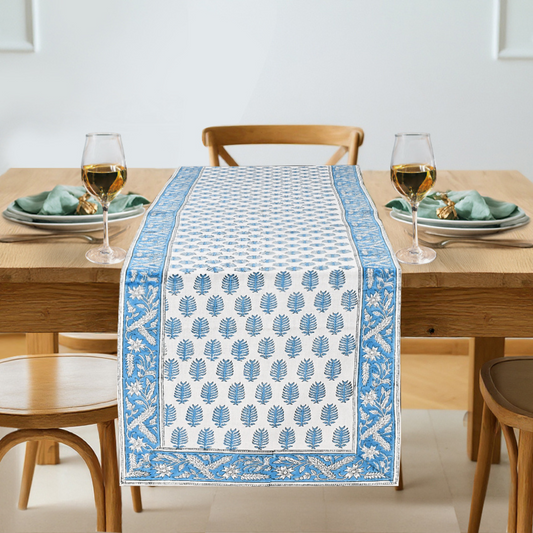 Table setting with a blue and white patterned table runner on a wooden table.