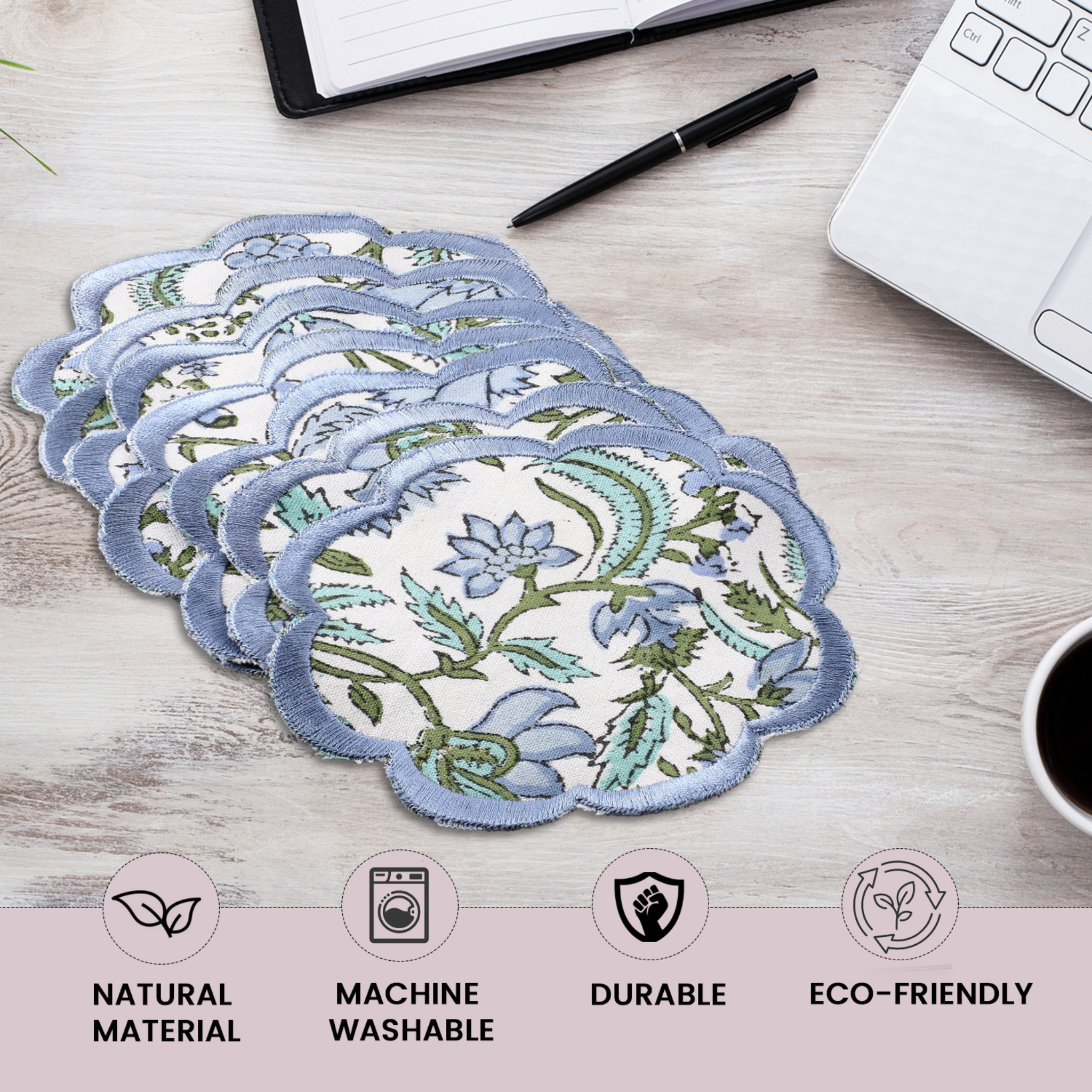 Set of floral coasters on a desk with laptop, pen, and coffee cup.