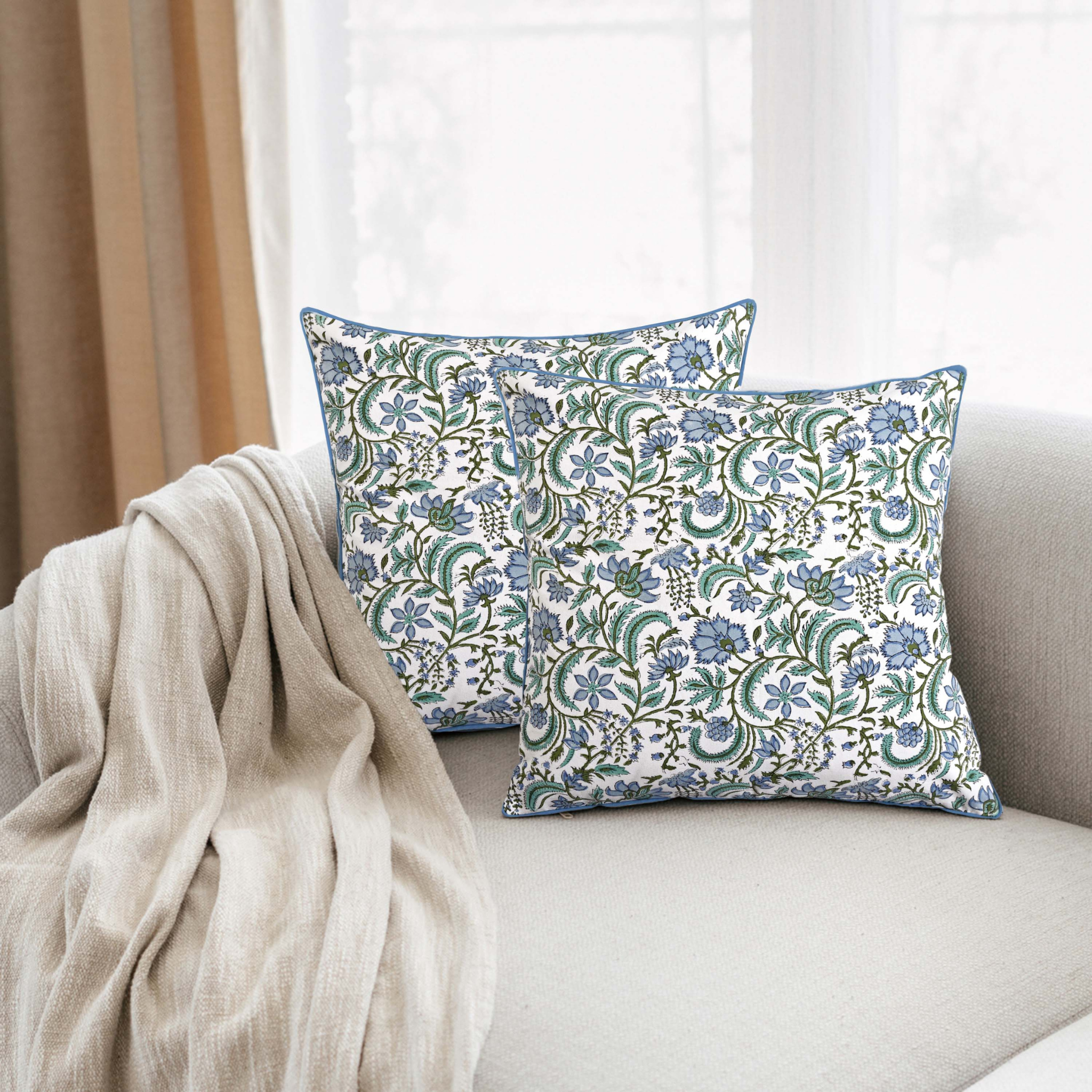 Floral patterned pillows on a sofa with a beige blanket