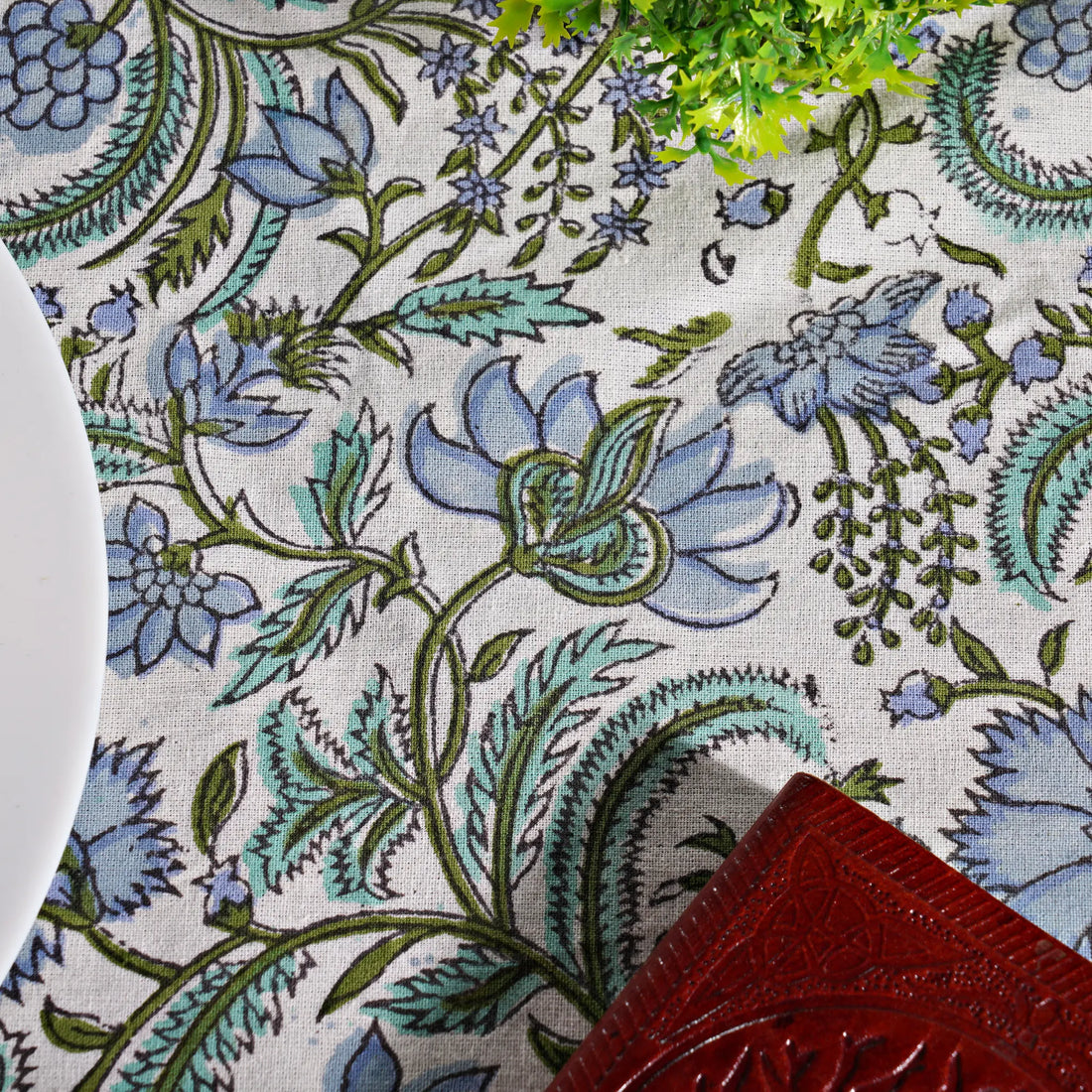 Close-up of a floral patterned fabric with blue and green flowers on a white background.