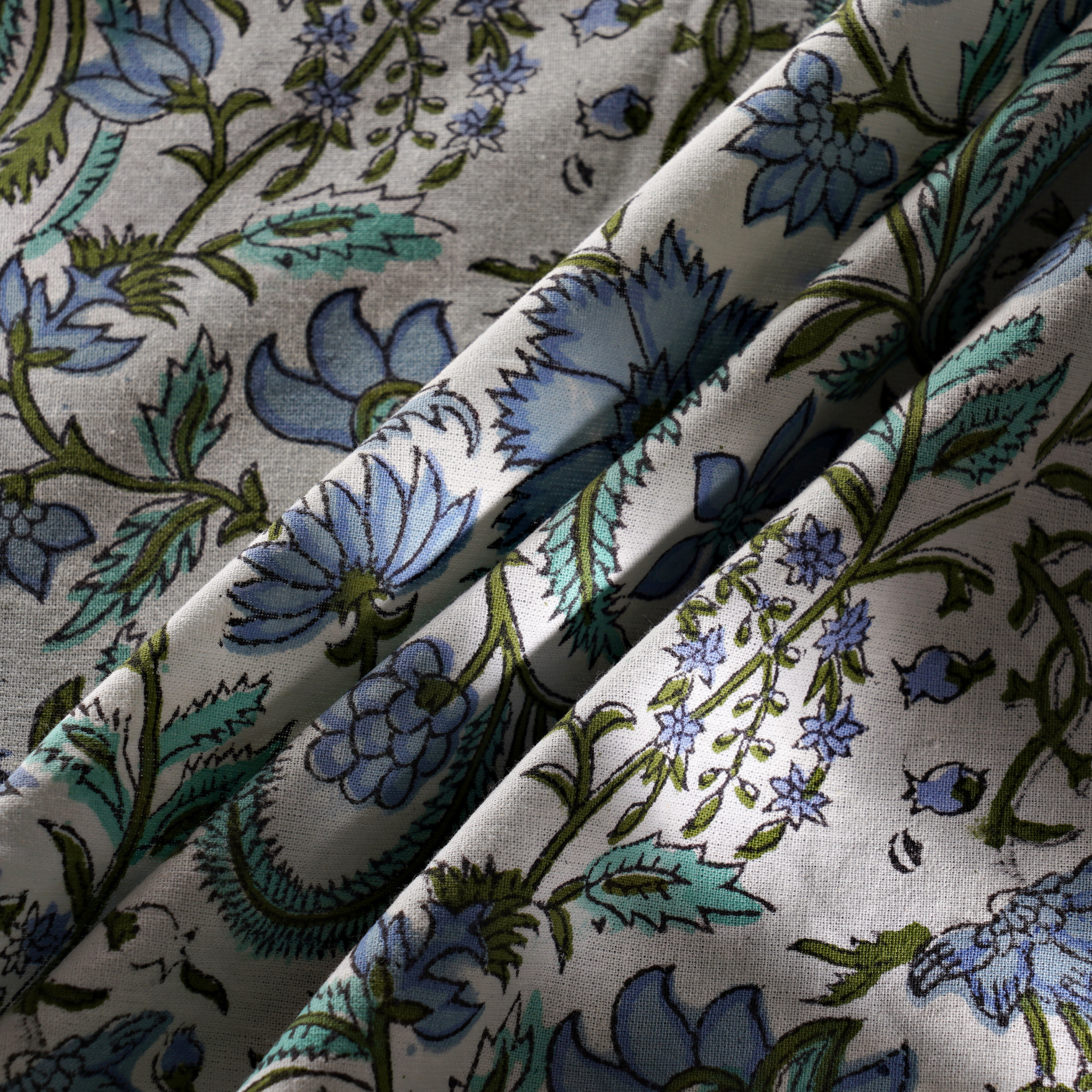 Close-up of floral fabric with blue and green flowers on a white background