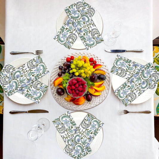 Table setting with patterned plates, napkins, and a fruit platter on a white tablecloth.
