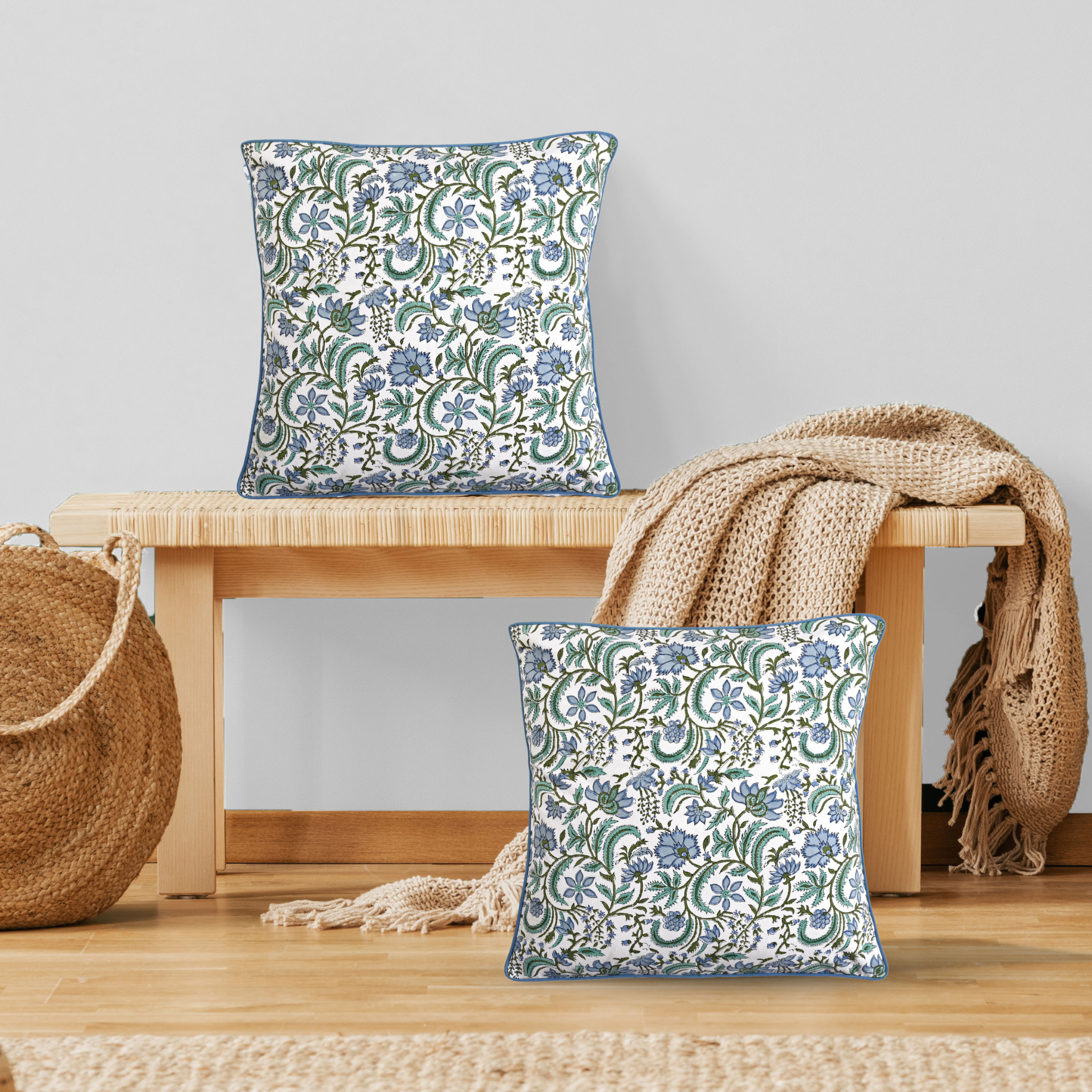 Floral patterned cushions on a wooden bench with a neutral background