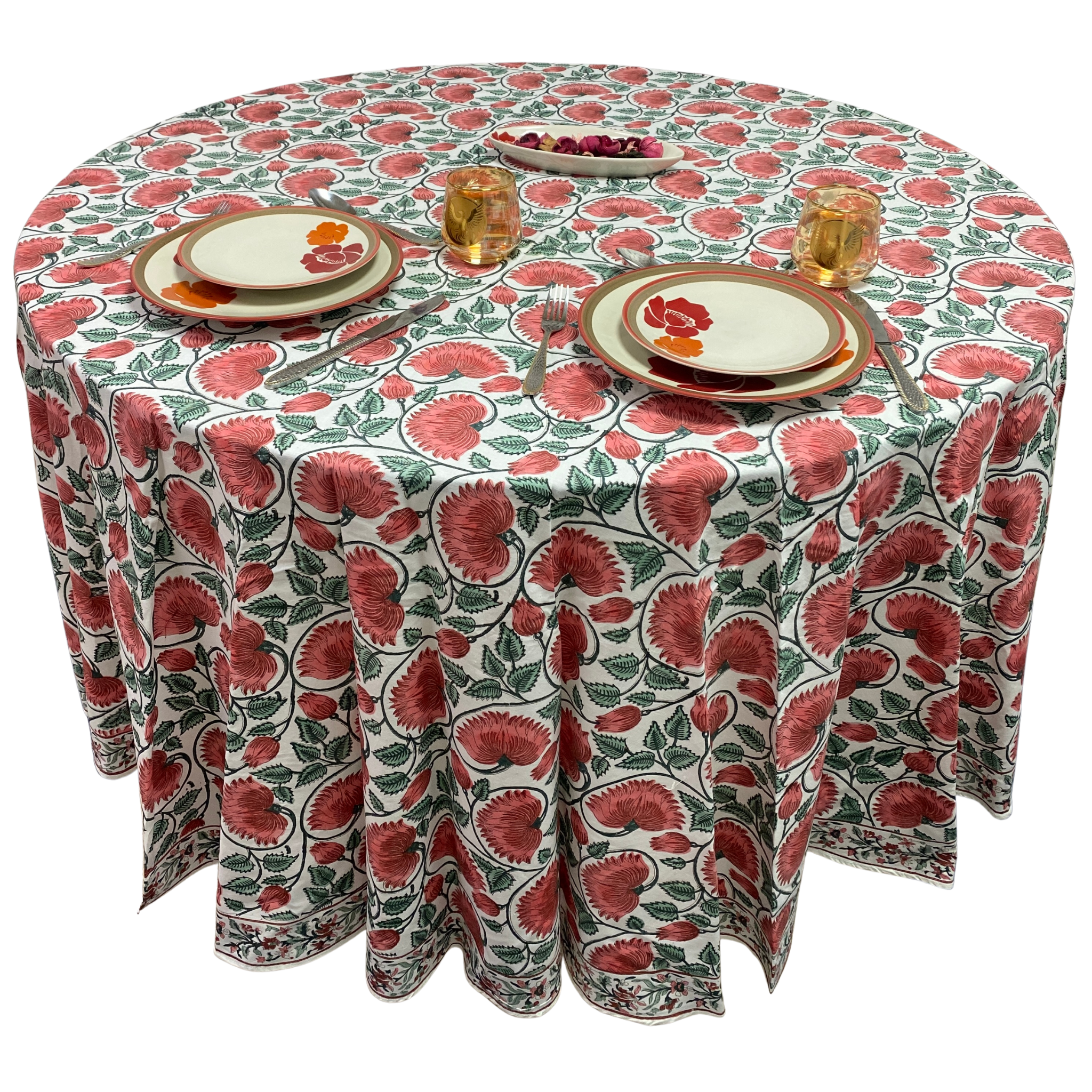 Round table with a floral patterned tablecloth, plates, and glasses on a white background
