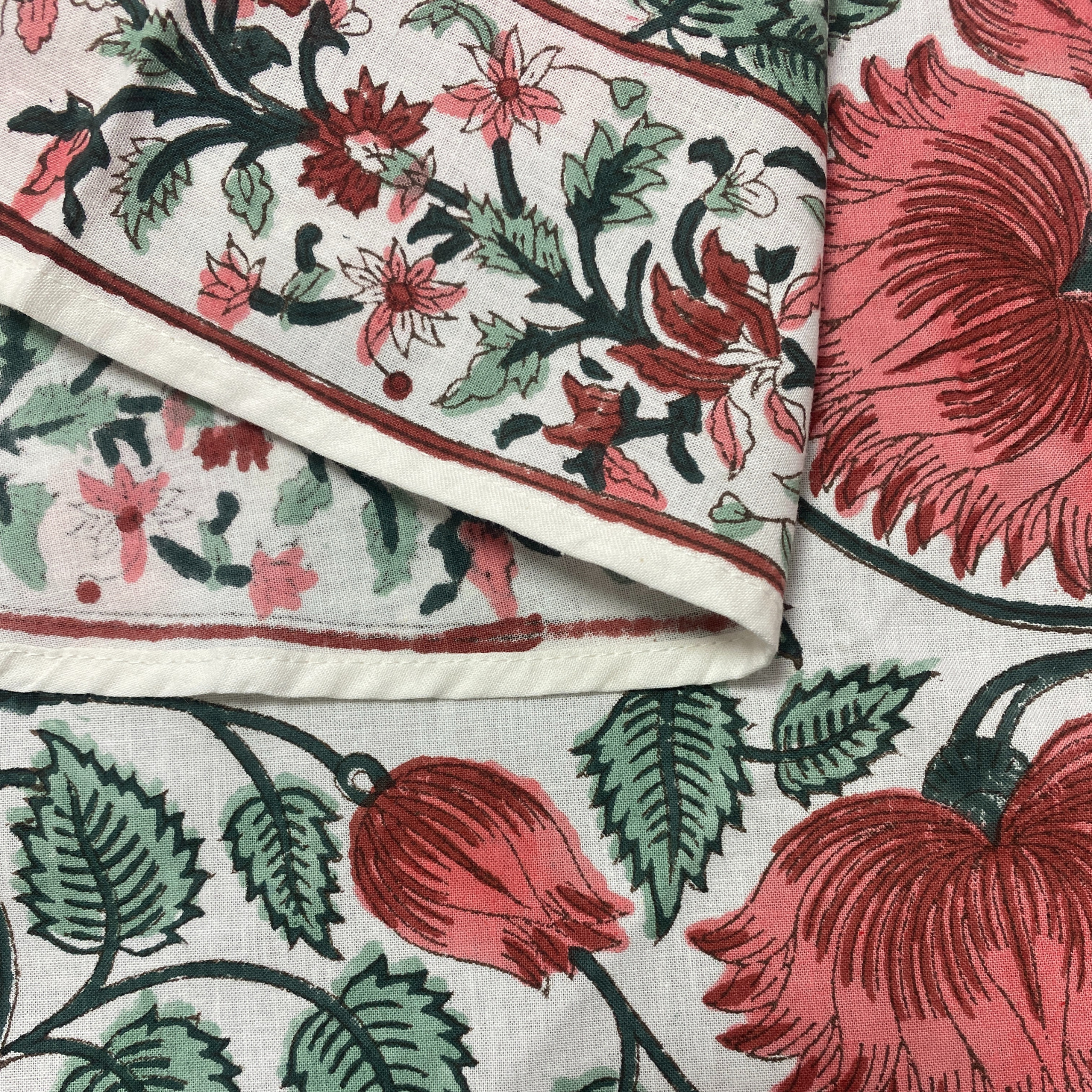 Close-up of floral fabric with red, green, and black patterns on a white background.