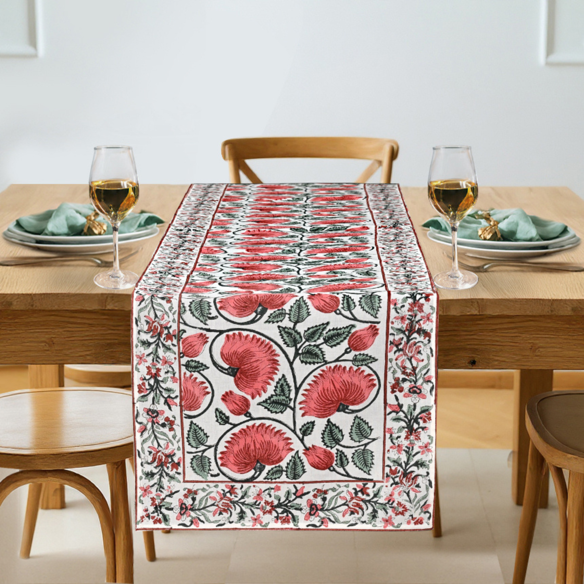 Floral table runner on a dining table with glasses and plates.