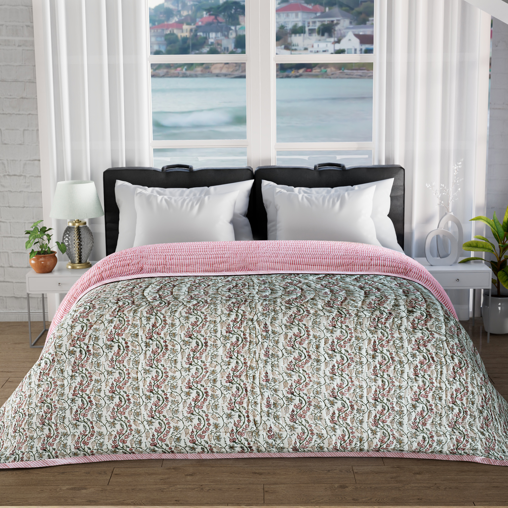 Bed with pink and green patterned comforter in a room with large windows showing a view of water and buildings.