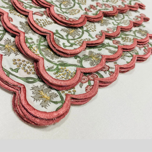 Set of decorative coasters with pink scalloped edges and floral patterns on a white surface