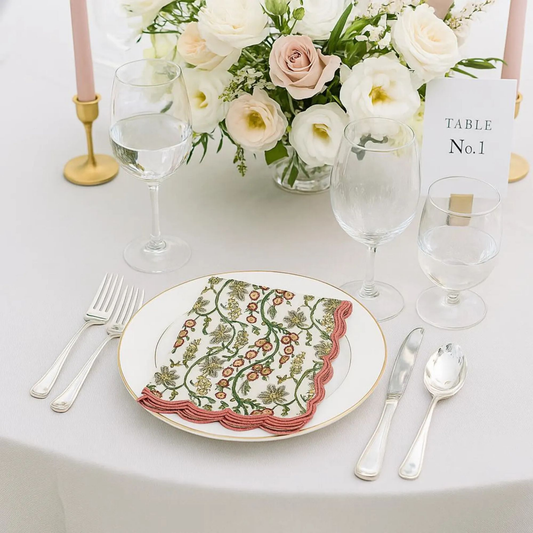 Elegant table setting with floral centerpiece, plates, cutlery, and glasses on a white tablecloth.