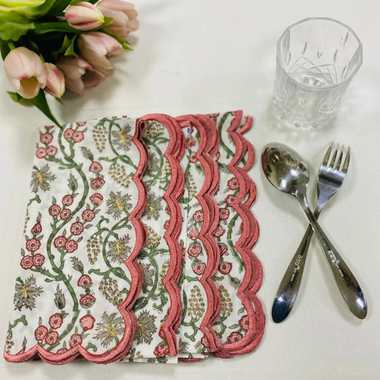Decorative floral napkin on a table with cutlery and a glass.