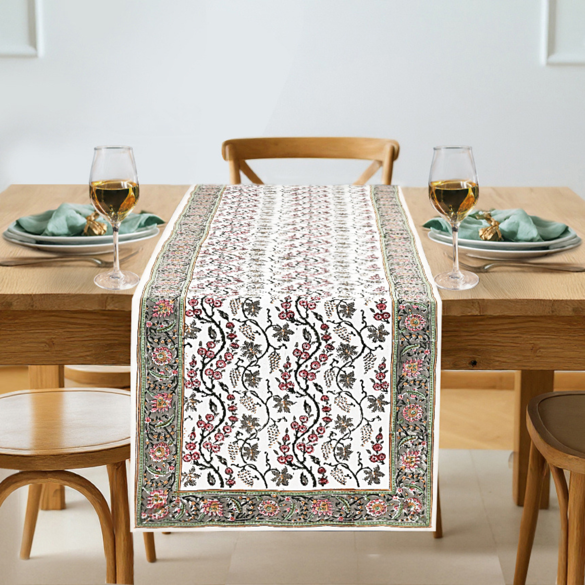 Dining table set with a decorative table runner, glasses, and plates.