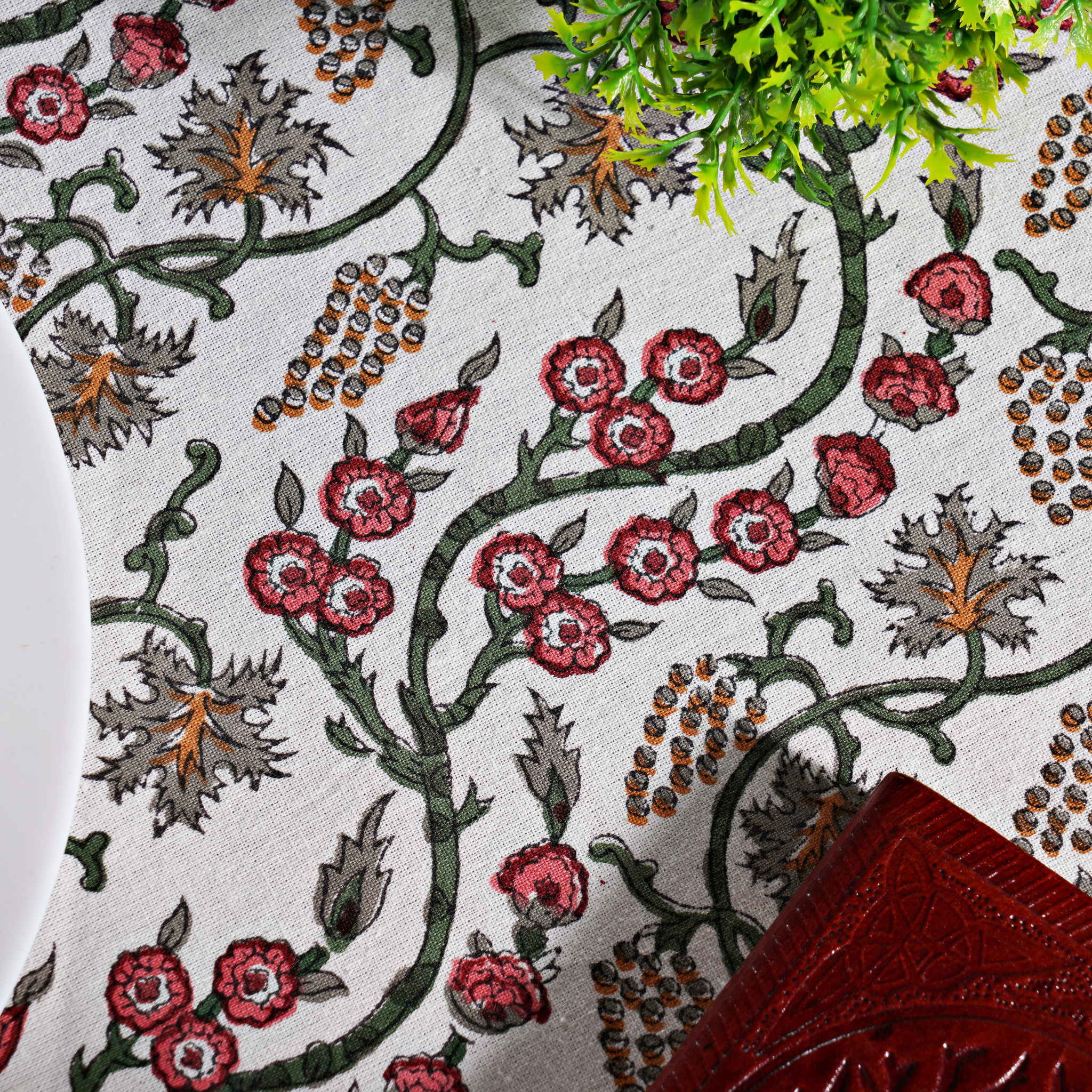 Close-up of a floral patterned fabric with red flowers and green leaves.