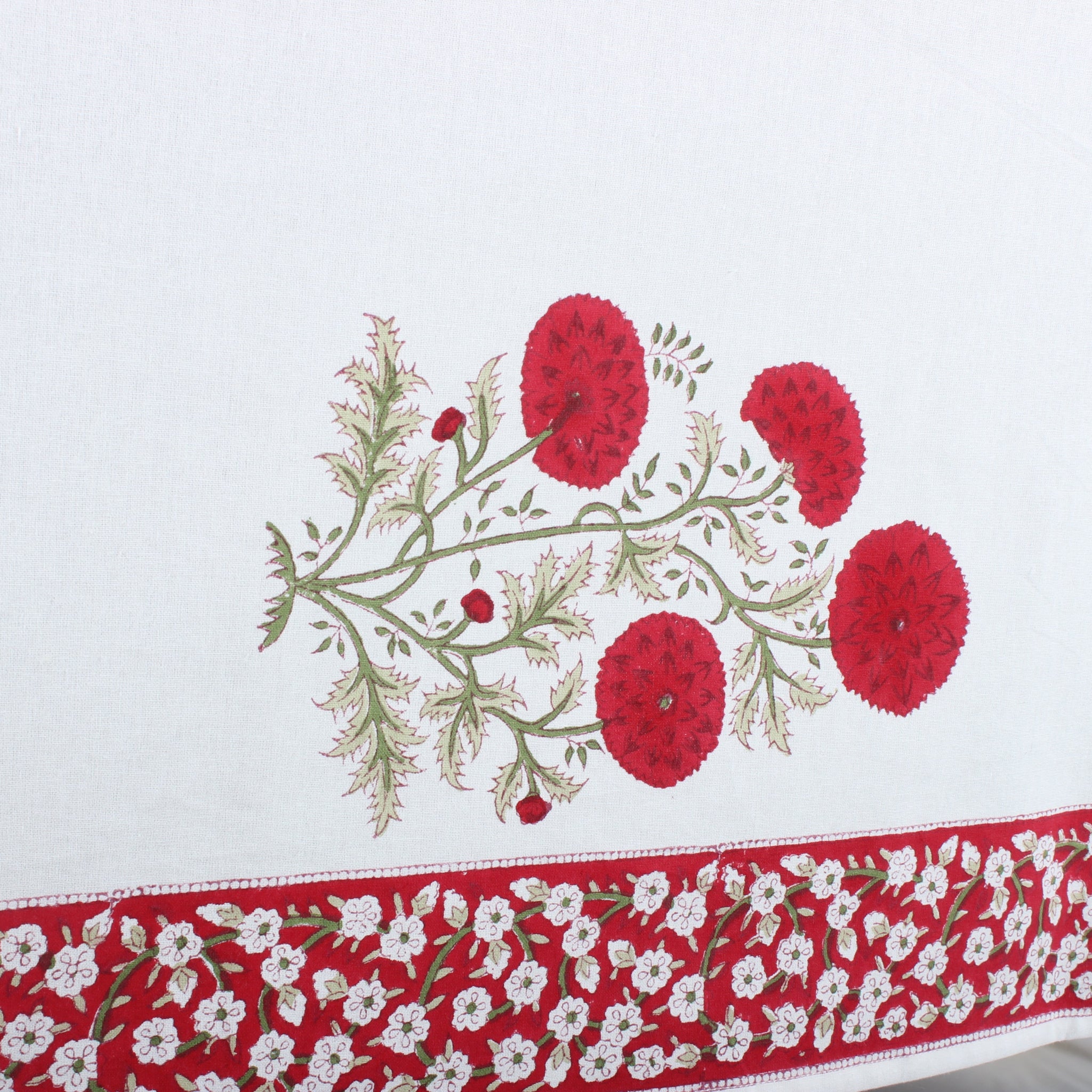 Embroidered tablecloth with red floral design on a white background
