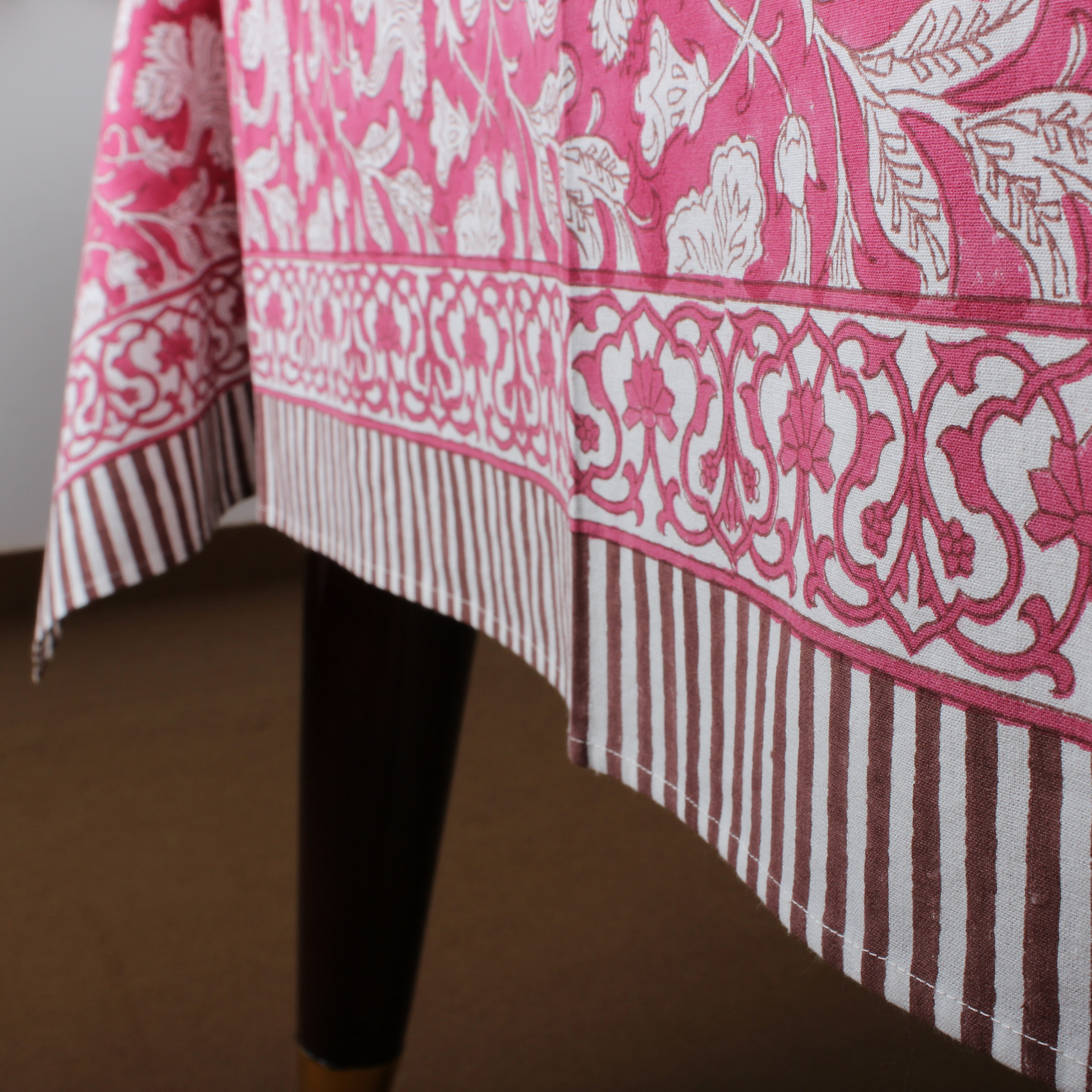 Close-up of a pink and white patterned tablecloth on a table.