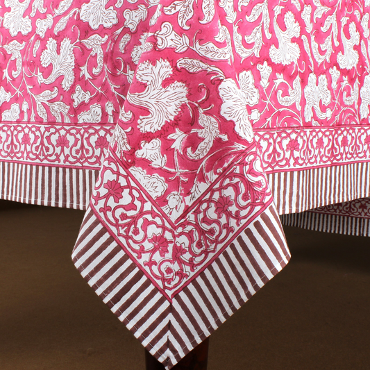 Pink and white patterned tablecloth with striped border on a brown background