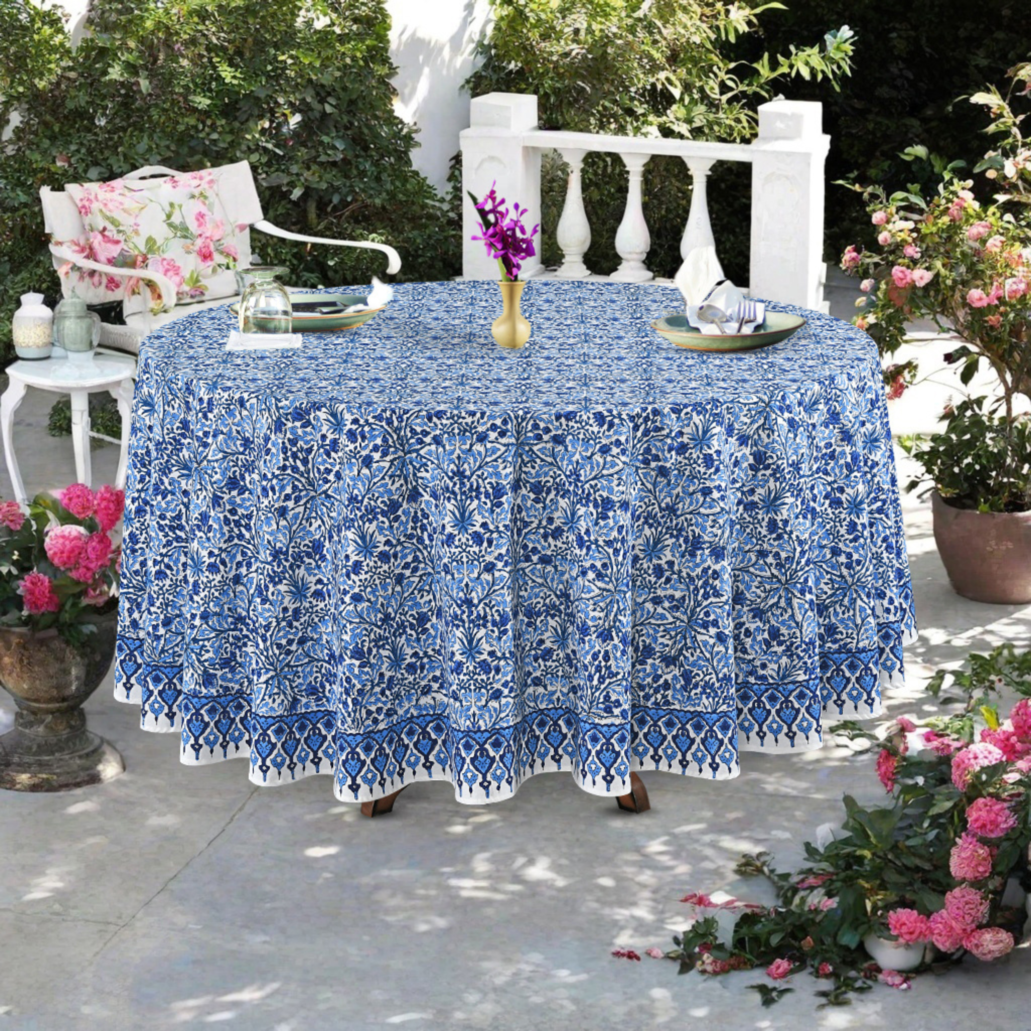 Round table with a blue floral tablecloth outdoors on a patio