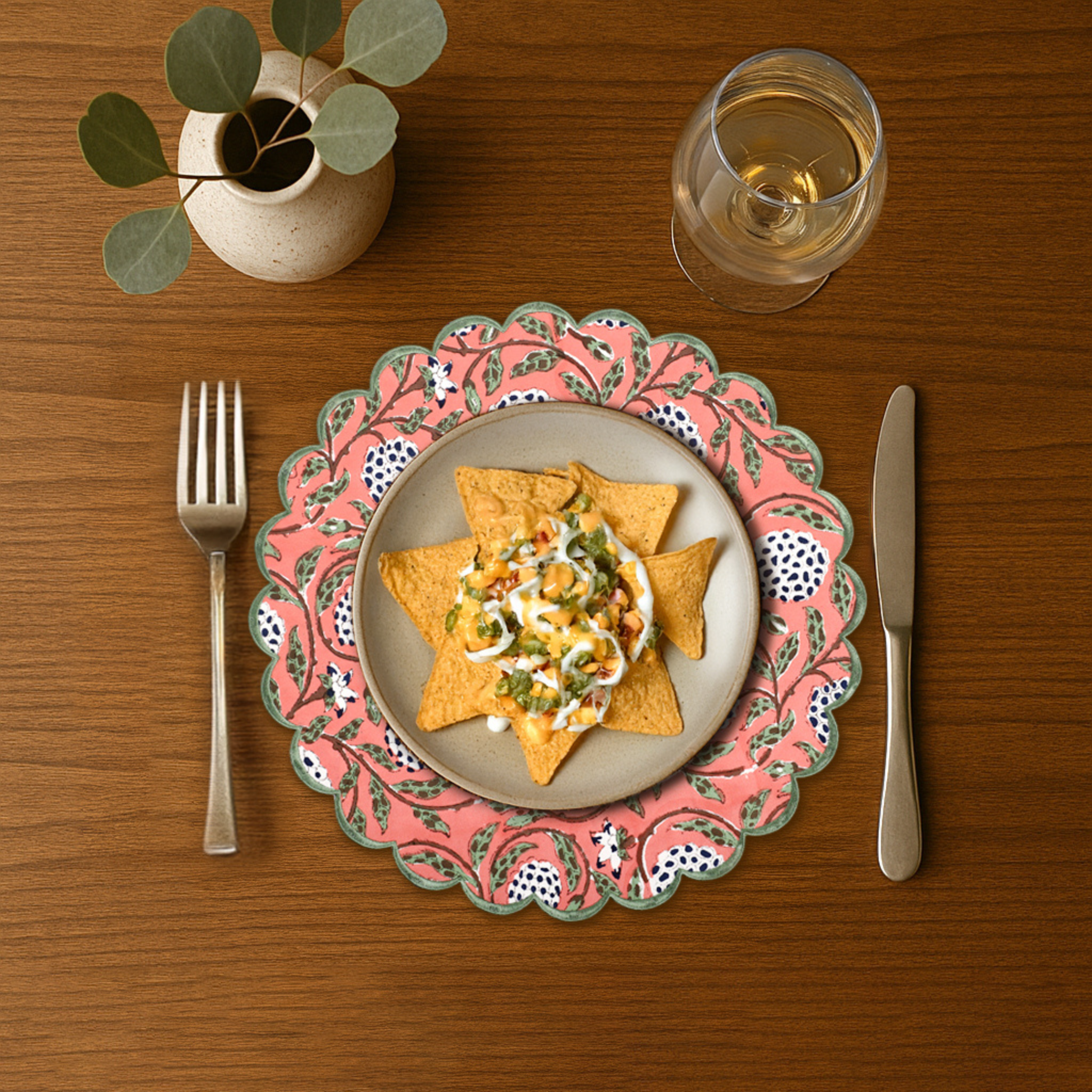 Dinner setting with a plate of food, cutlery, and a glass on a wooden table.