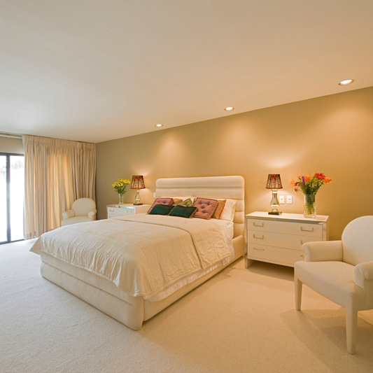 Neatly arranged bedroom with a bed, nightstands, and chairs.