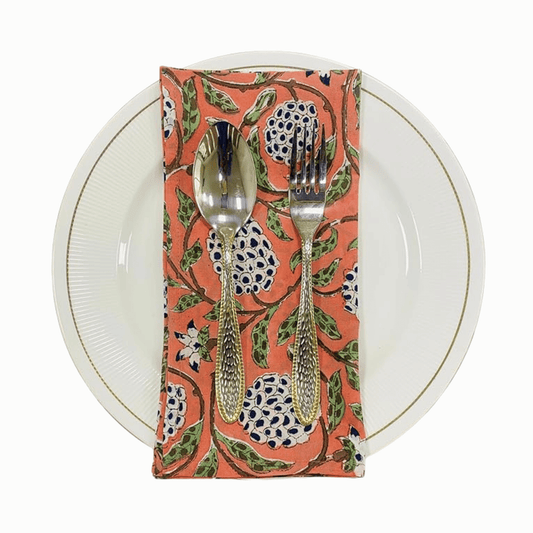 Napkin with floral pattern holding a spoon and fork on a white plate.