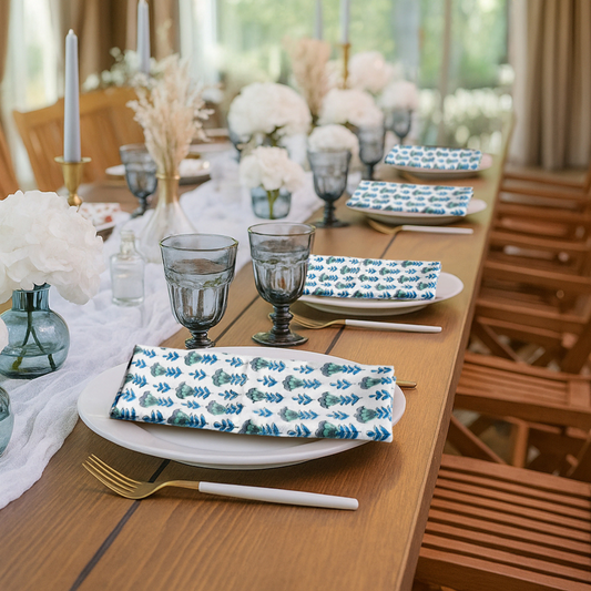 Elegant table setting with floral napkins, glasses, and cutlery on a wooden table.